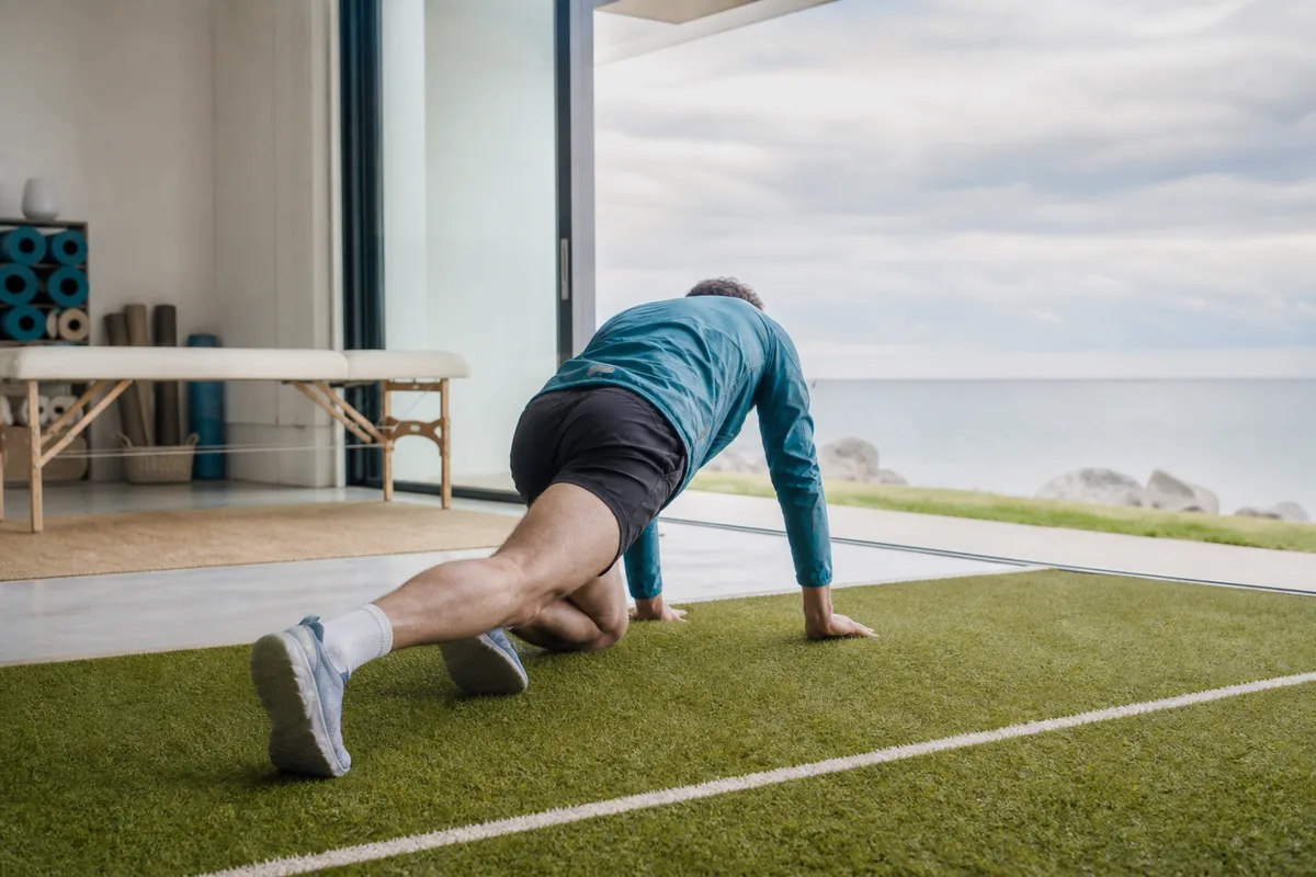 Athlète amateur en position d&rsquo;appui fléchi sur un terrain d&rsquo;entraînement extérieur